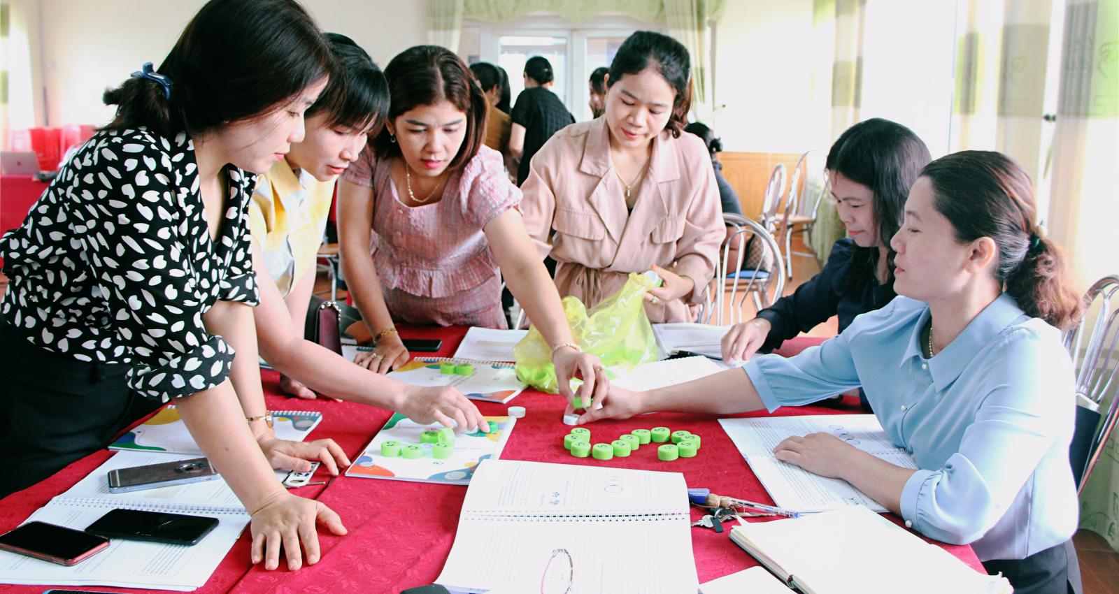A group of Vietnamese women participating in a group workshop around a table.