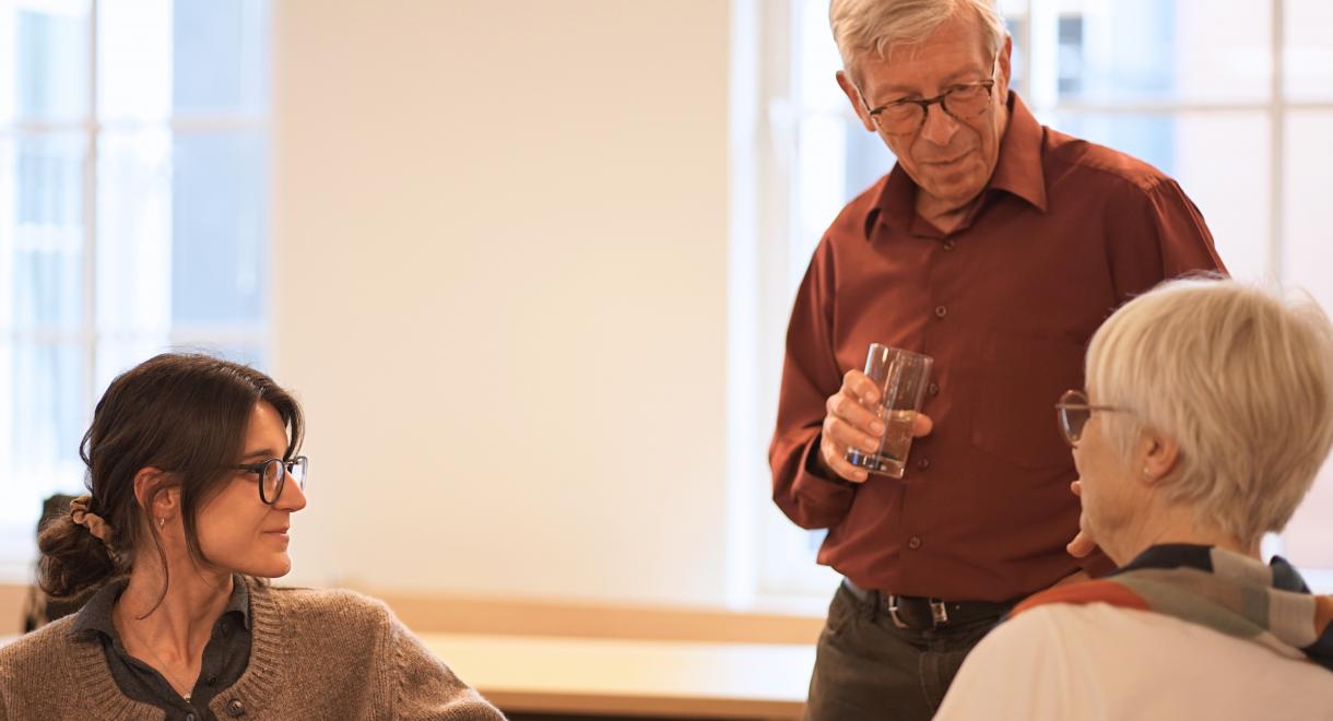 A man and woman are discussing something with an older woman, who appears engaged and responsive to their dialogue.