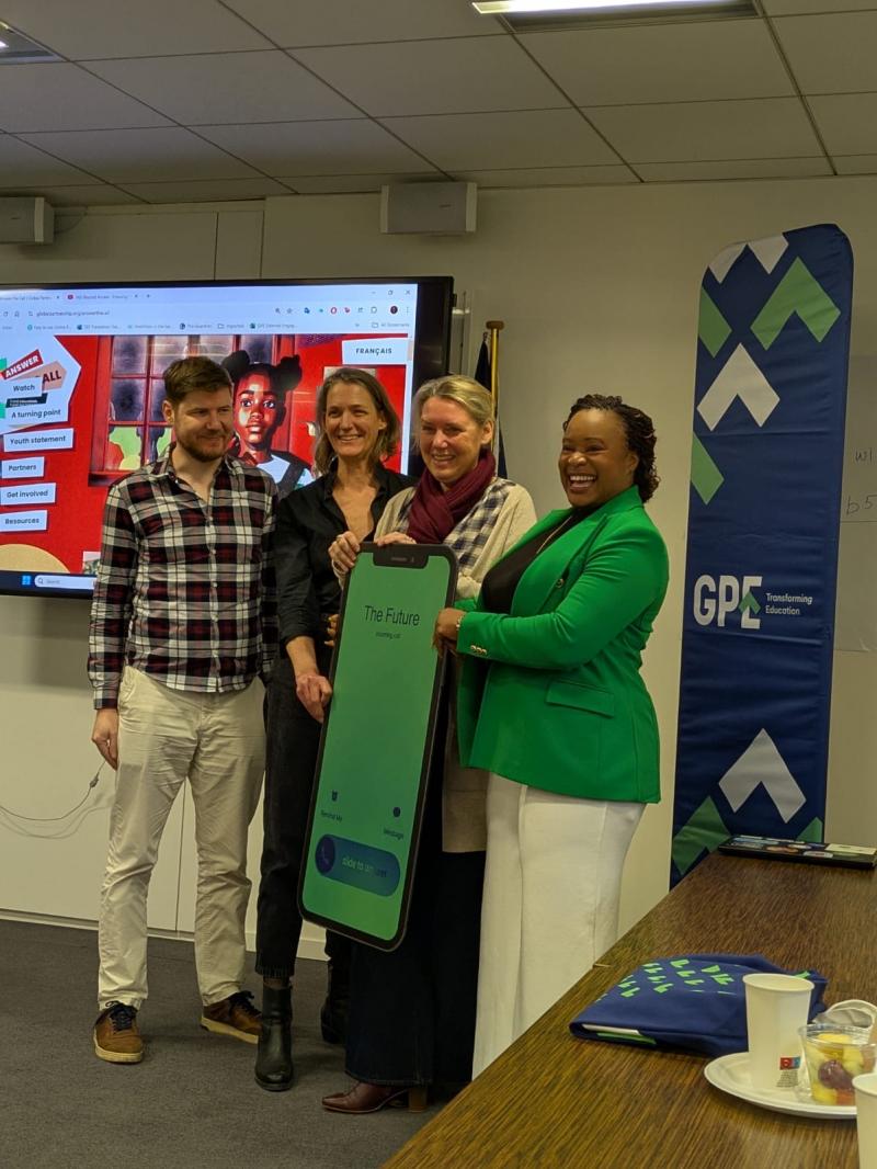 four people during a meeting posing for a picture with a giant cardboard phone