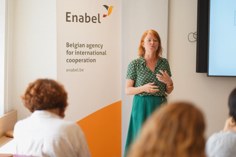 A woman stands before a group, delivering a presentation and interacting with her audience.