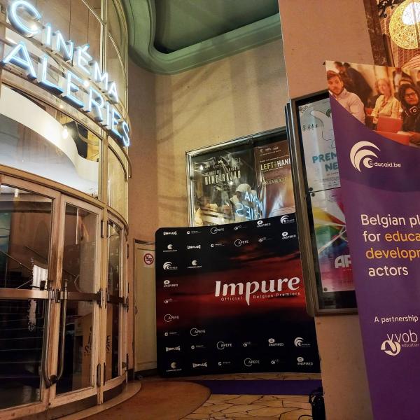 A cinema entrance with a photo wall from Impure and a purple banner with Educaid.be