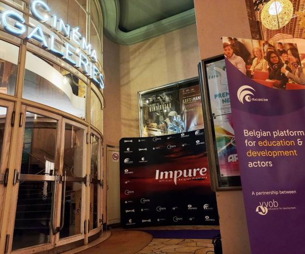 A cinema entrance with a photo wall from Impure and a purple banner with Educaid.be